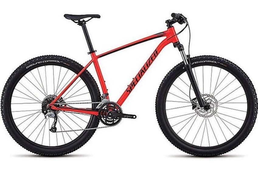 A red mountain bike with the brand name 'Specialized' on the frame, a gear system, and knobby tires. 4