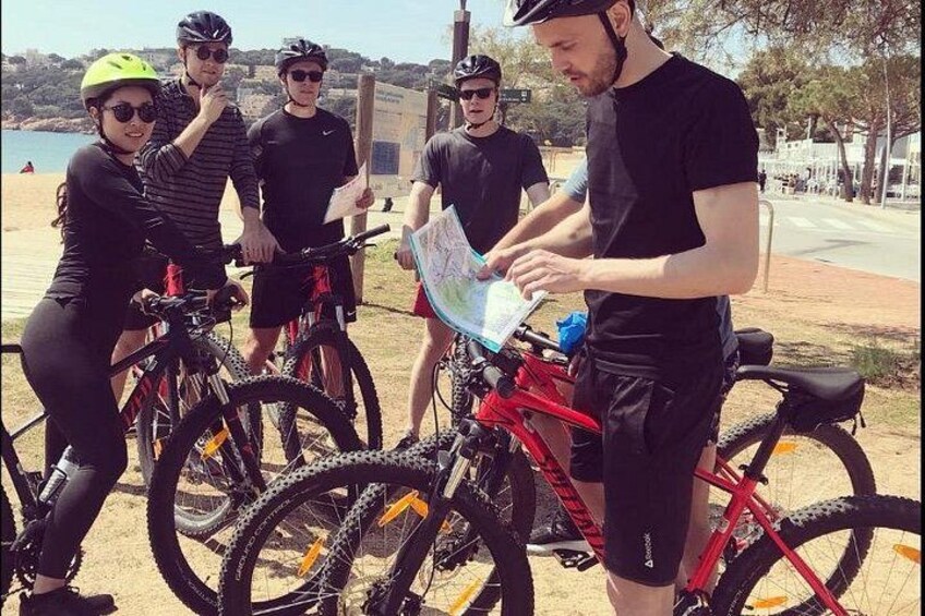 A group of people with bicycles, a map, and a red motorcycle. 3