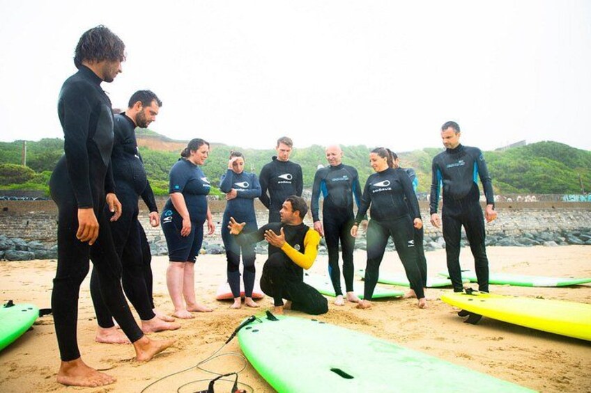 A group of people in wetsuits on a beach with surfboards. 4