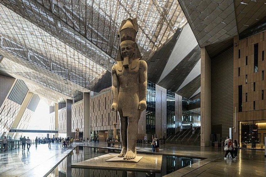 A large statue in a modern building with a glass ceiling and a reflective floor. 5