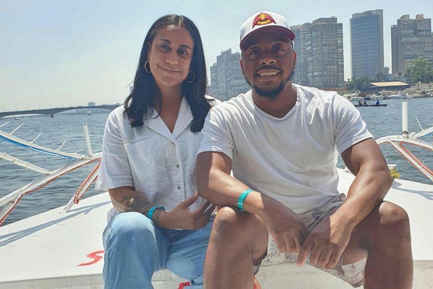 Dos personas sentadas en un bote con un horizonte urbano al fondo. 4