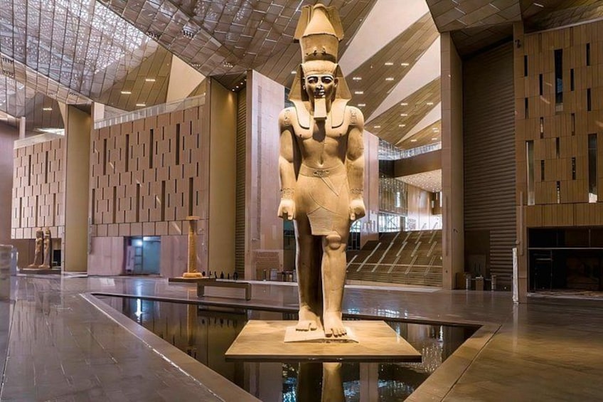 A large statue in a modern building with a reflective floor. 2