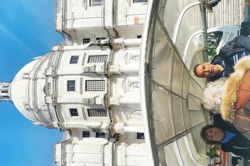 A historic building with classical architecture, a dome, and a person in a fur-lined coat. 4