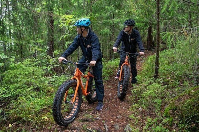 Two people riding mountain bikes on a forest trail. 1