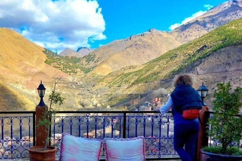 A person overlooking a mountainous landscape with a railing and potted plants. 1