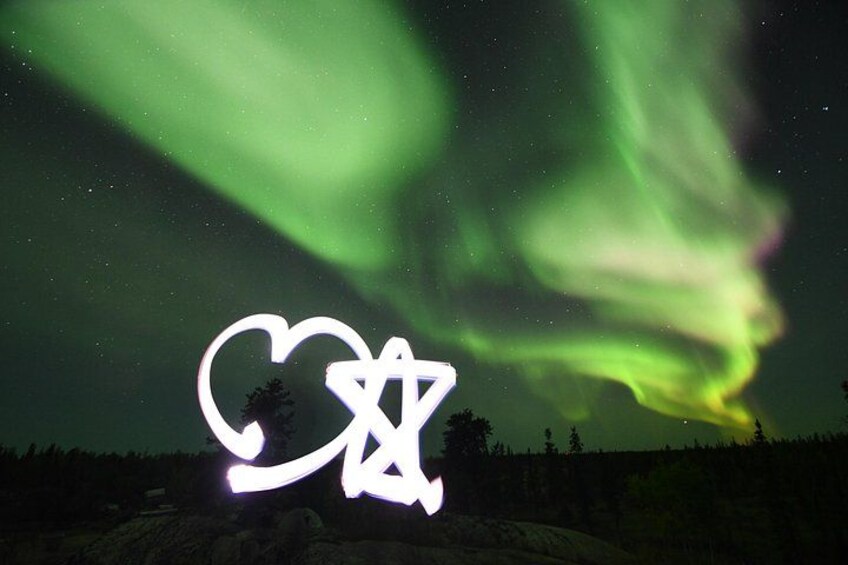 Auroras boreales sobre un paisaje con un símbolo de corazón y una estrella de David. 2