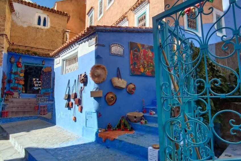 Un edificio azul con una tienda, una reja metálica y varios artículos exhibidos en la pared. 2