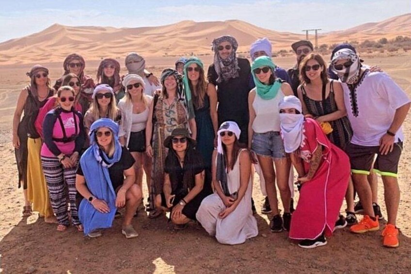 A group of people in a desert landscape with sand dunes in the background. 4