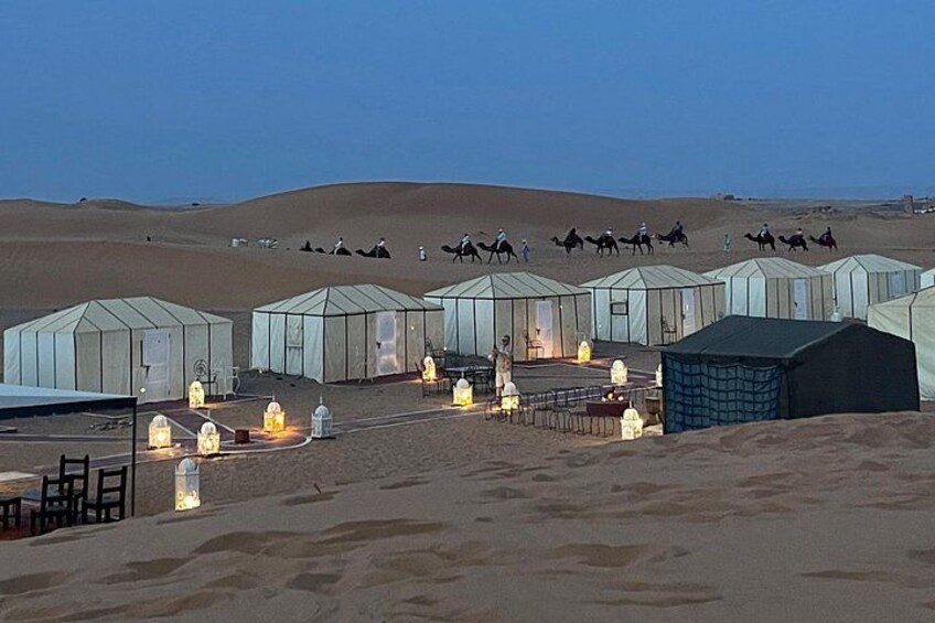 A desert landscape with tents and camels. 3