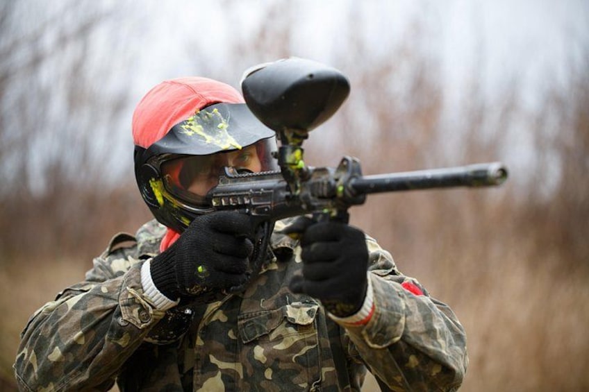 Una persona con ropa de camuflaje apuntando con una pistola de paintball. 1