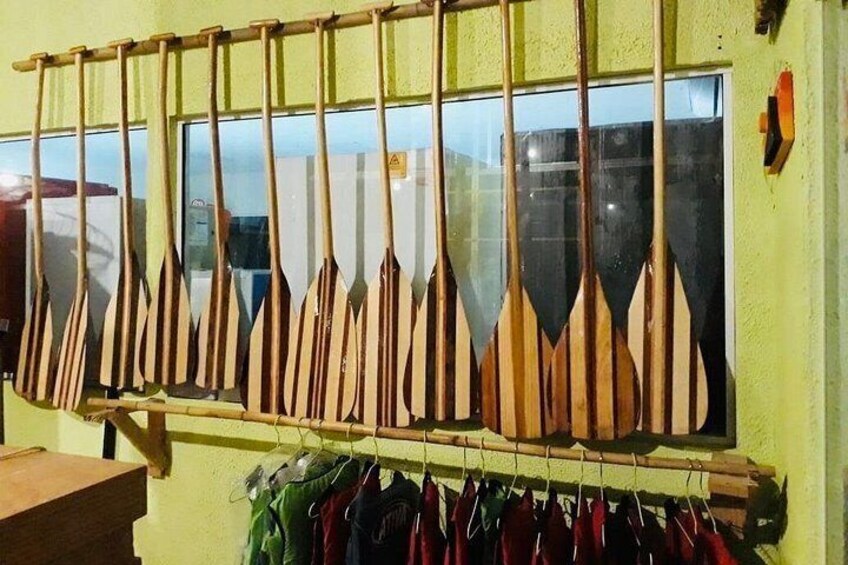 Una fila de palas de madera colgadas en un soporte, una ventana con reflejos y una mesa de madera. 4