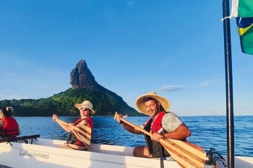 Un bote con dos personas remando, cielo azul despejado y una montaña al fondo. 5