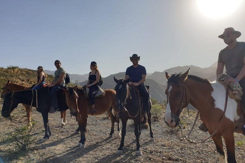 Quattro persone a cavallo in una giornata limpida, con montagne sullo sfondo. 1