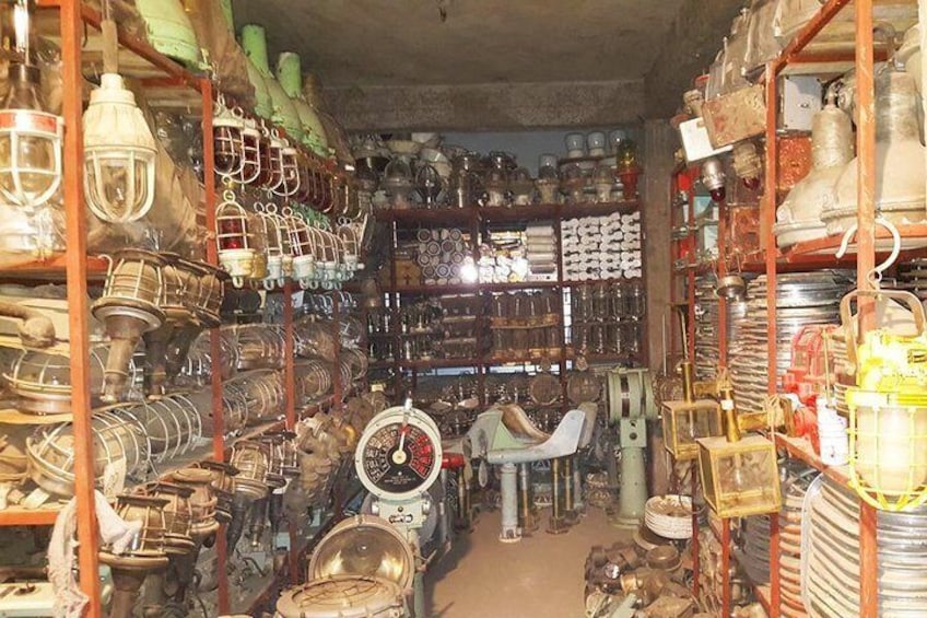 A cluttered antique shop with shelves filled with various metal objects and household items. 3