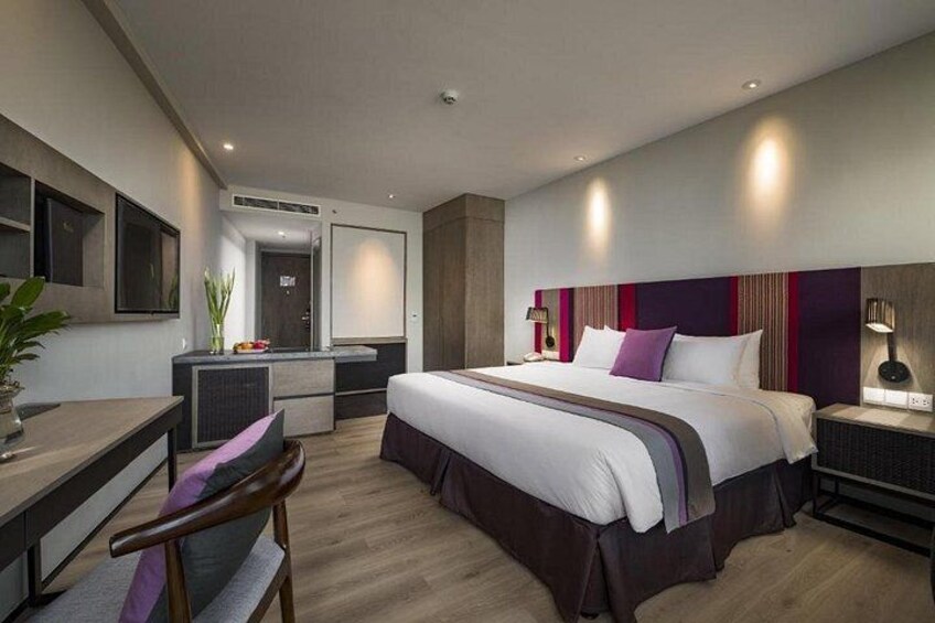 A modern hotel room with a large bed, bedside tables, a desk, and a chair. 2