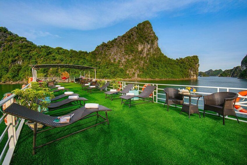 A deck with lounge chairs and a table, overlooking a body of water and a mountainous landscape. 5