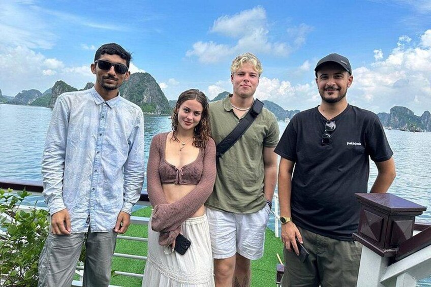 Four people standing by a body of water with a mountainous landscape in the background. 3