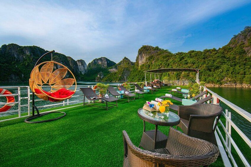 A boat deck with wicker chairs, a hanging chair, and a table with drinks. 4