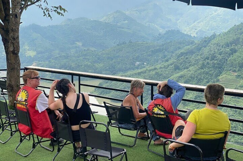 People sitting on chairs overlooking a mountainous landscape. 3