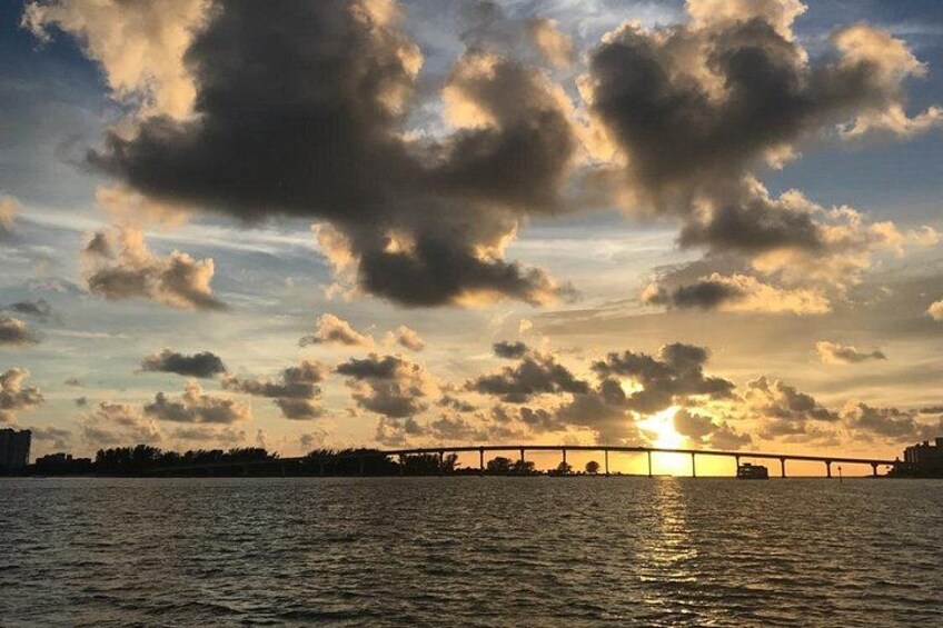 A sunset over a body of water with a bridge in the distance. 3