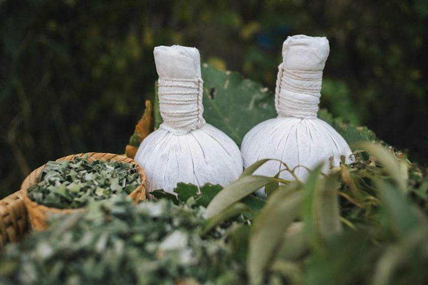 Two white, tied bundles of herbs in a natural setting with a basket of chopped herbs nearby. 4