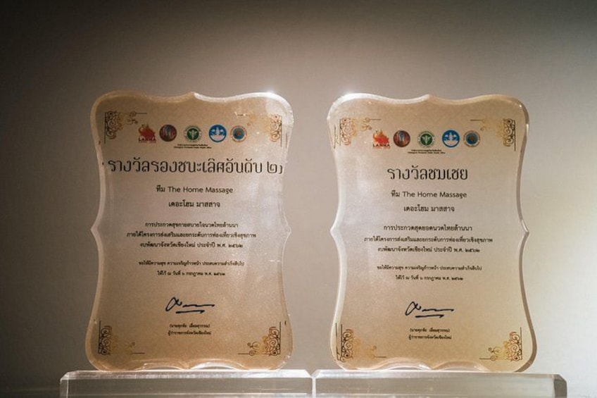 Two awards with text in a foreign language, placed on a stand. 2