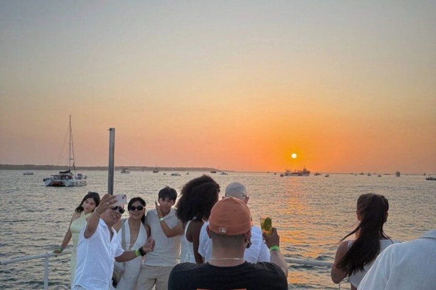 A sunset over a body of water with boats and people on a dock. 4
