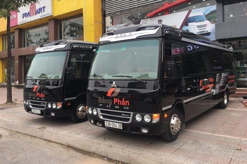 Two black buses parked on a street in front of a building with a sign that reads "FIM MART". 4