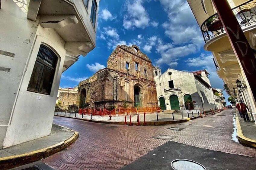 A historic building with arched windows and a brick facade, surrounded by a cobblestone street and modern buildings. 2