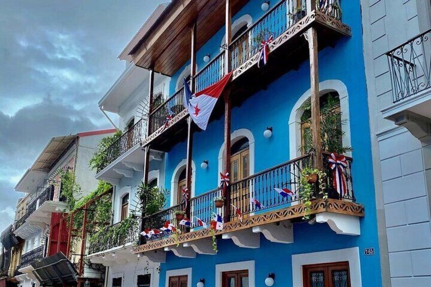 A blue building with balconies adorned with flags and plants. 5