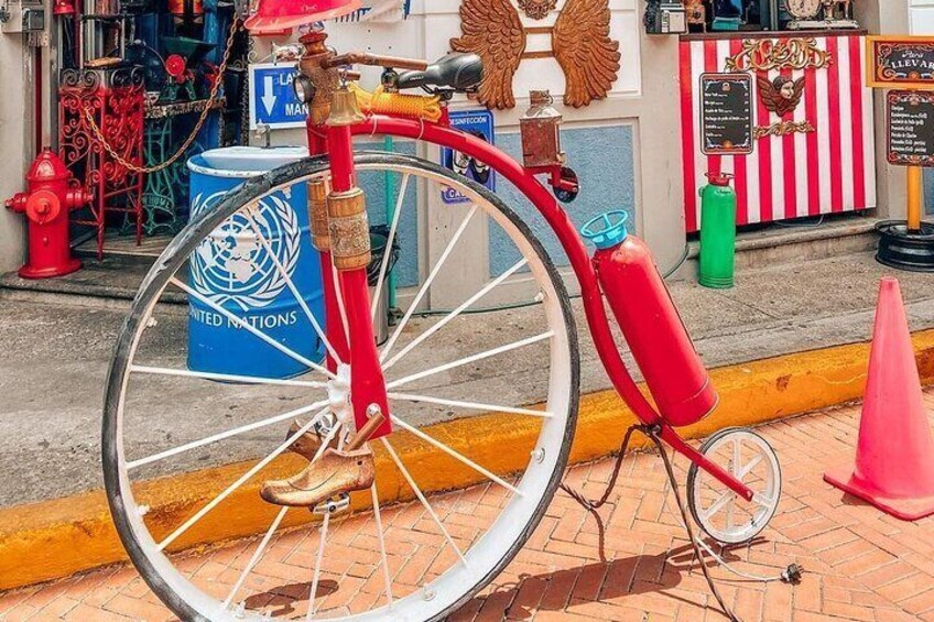 A red bicycle with a large wheel, a gas canister, and a UNITE D NATIONS barrel. 3