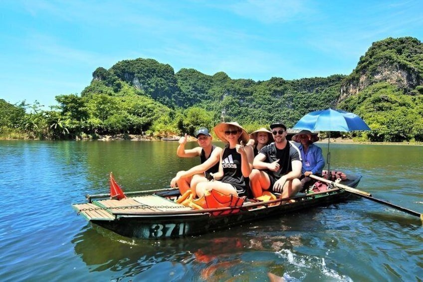 A group of people on a boat with a number 371 on it, surrounded by a forested landscape. 3