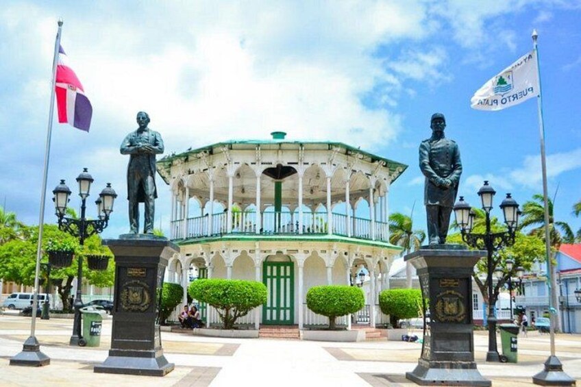 Un pabellón con estatuas, una bandera y un edificio con puerta verde. 1