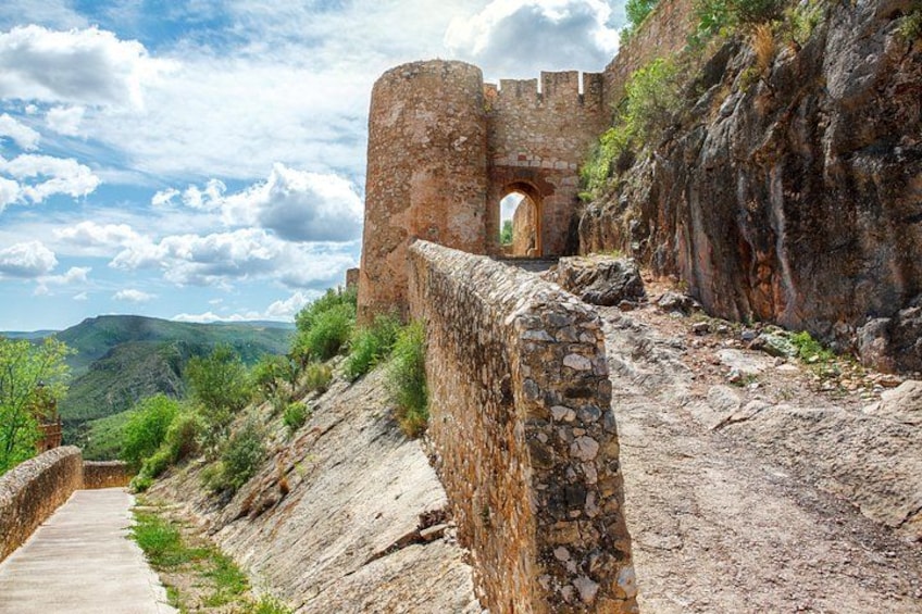 A stone wall, a stone archway, and a pathway leading to a castle. 4