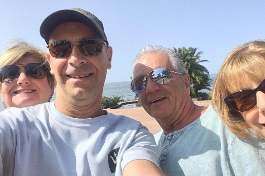 Un grupo de personas al aire libre, posiblemente en una playa o zona costera, con cielos despejados y palmeras al fondo. 5