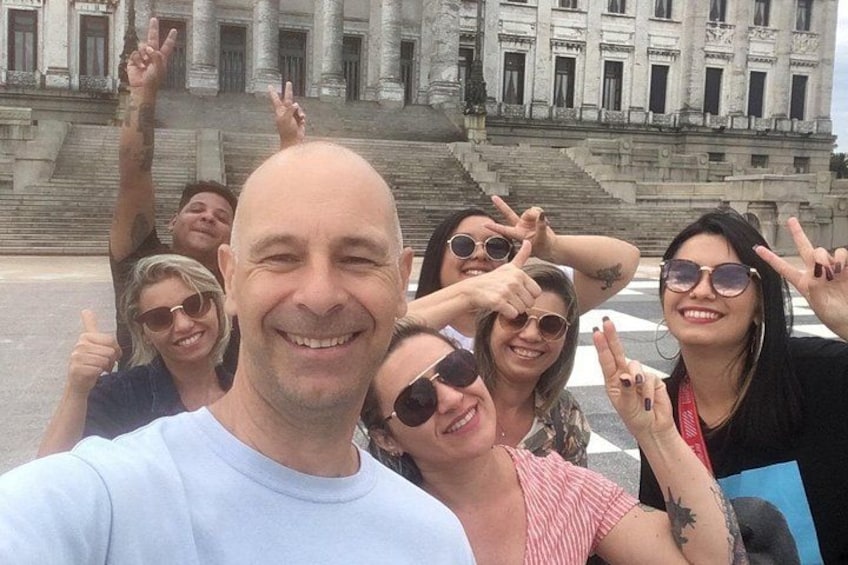 Un grupo de personas posando frente a un edificio grande de estilo clásico, con columnas y escalones. 2