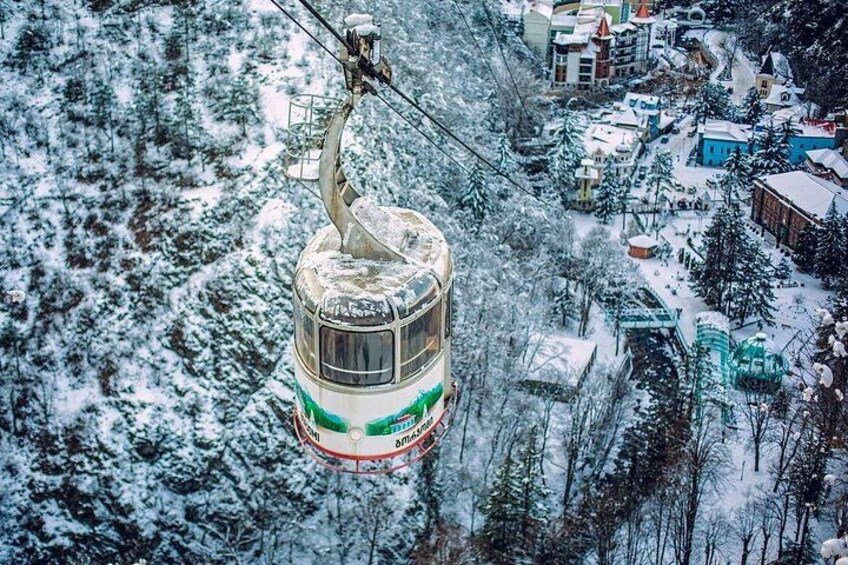 Un teleférico suspendido sobre un paisaje nevado con edificios abajo. 1
