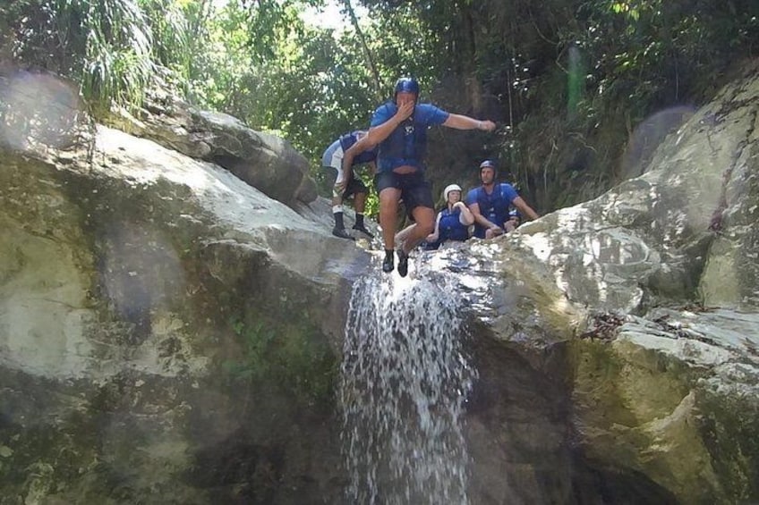 Iemand springt van een rots in een waterval. 4