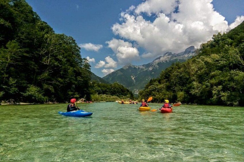 Kayakistas en un río cristalino rodeado de exuberante vegetación y montañas. 1