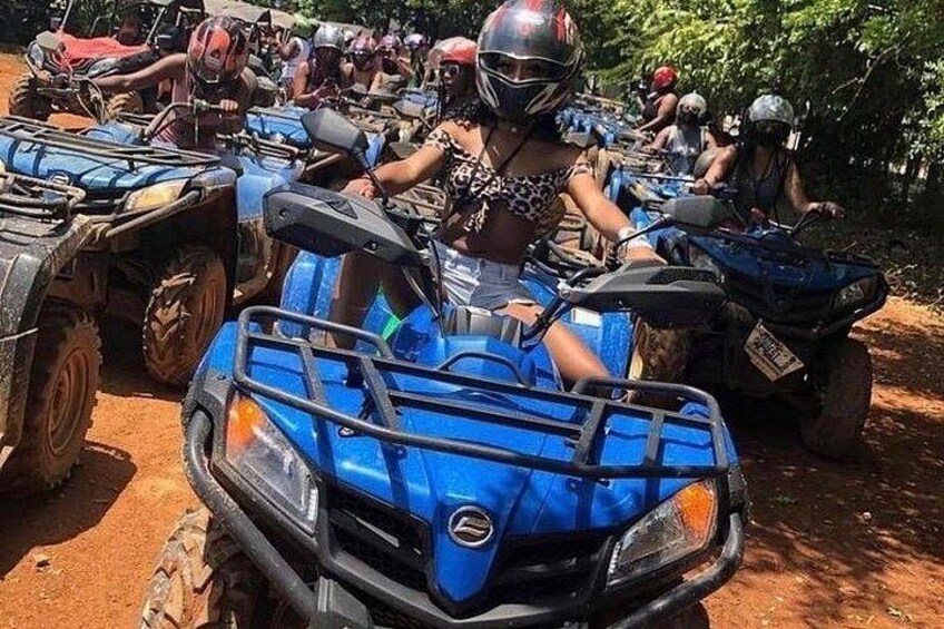 A group of people on ATVs in a dirt area with trees in the background. 1