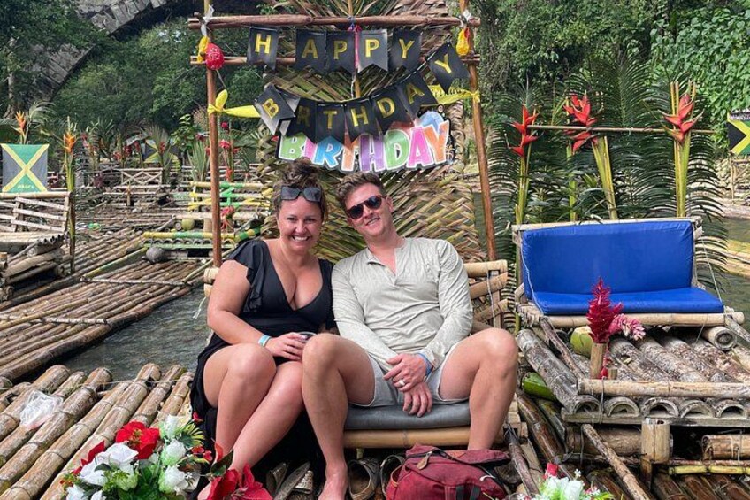 A couple sitting on a floating platform with a 'Happy Birthday' banner. 3