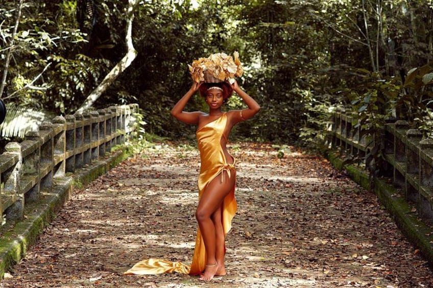 Une personne vêtue d’une robe jaune se tient sur un sentier recouvert de feuilles, avec un pont en arrière-plan. 3