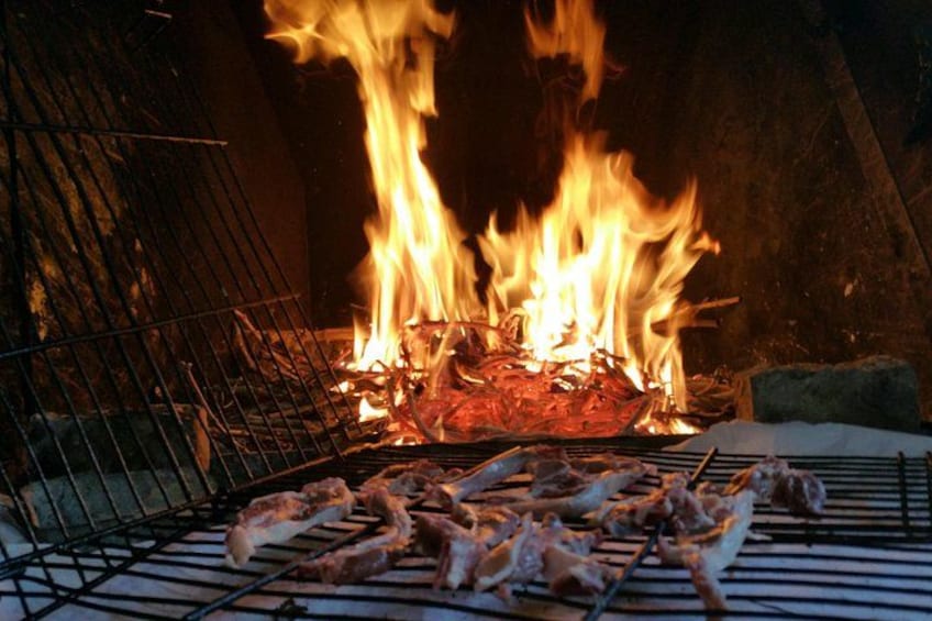 Een barbecue met vlees dat boven een open vuur wordt bereid. 2