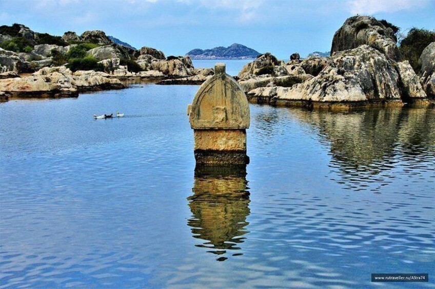 A calm body of water with a stone structure in the center, surrounded by rocks and a distant mountain. 3