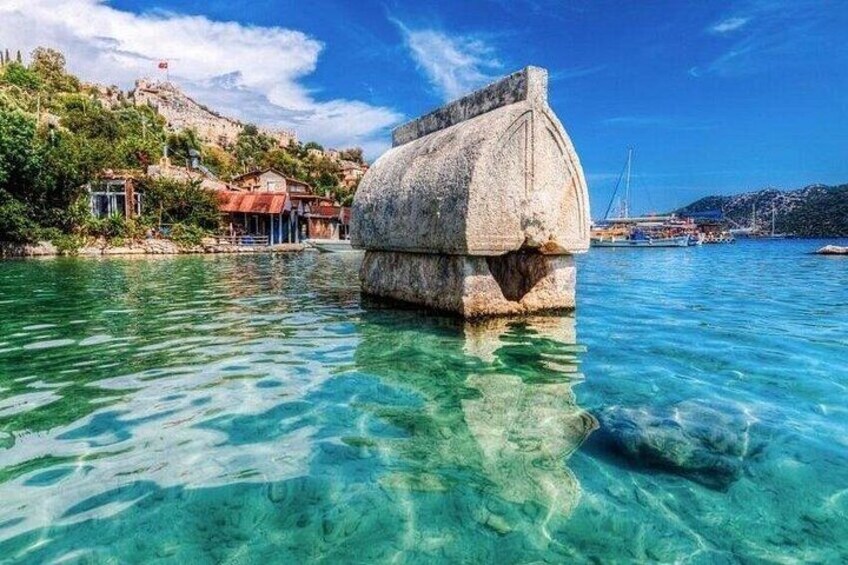 Un mar azul transparente, una construcción de piedra y edificios en una colina. 2
