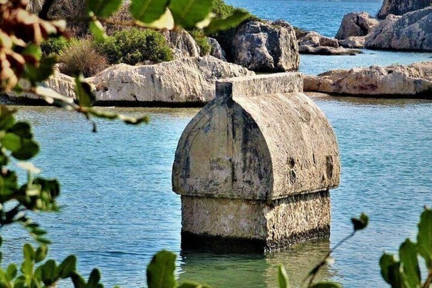 A concrete structure with a rounded top, surrounded by water and rocks. 2