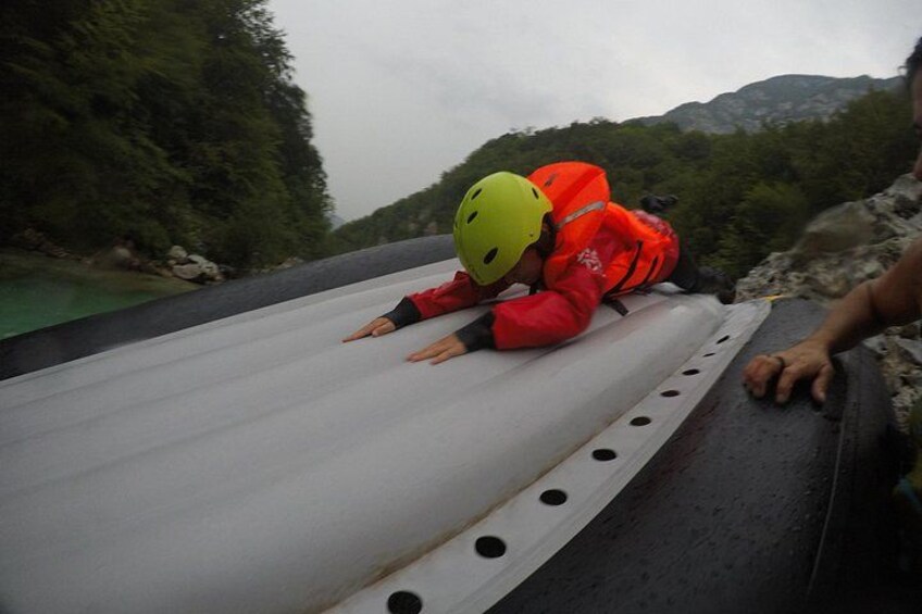 Eine Person mit roter Jacke und gelbem Helm liegt draußen auf einer weißen Fläche. 1