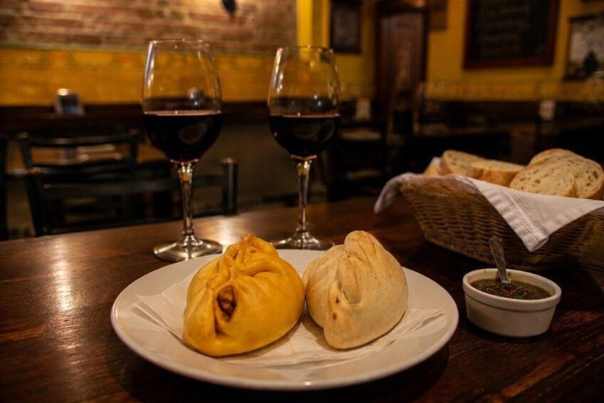 A plate with two pastries and two glasses of red wine on a wooden table. 1