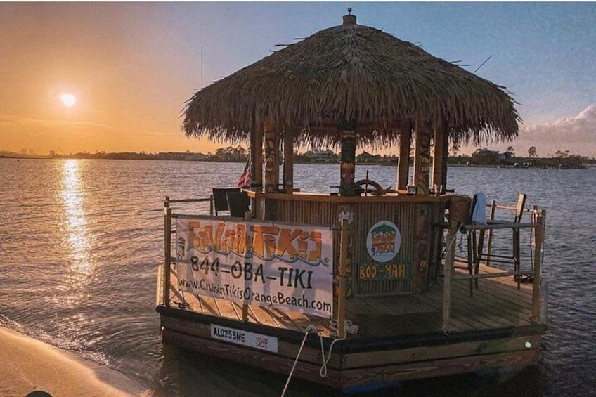 A wooden boat with a thatched roof, docked at sunset. 3