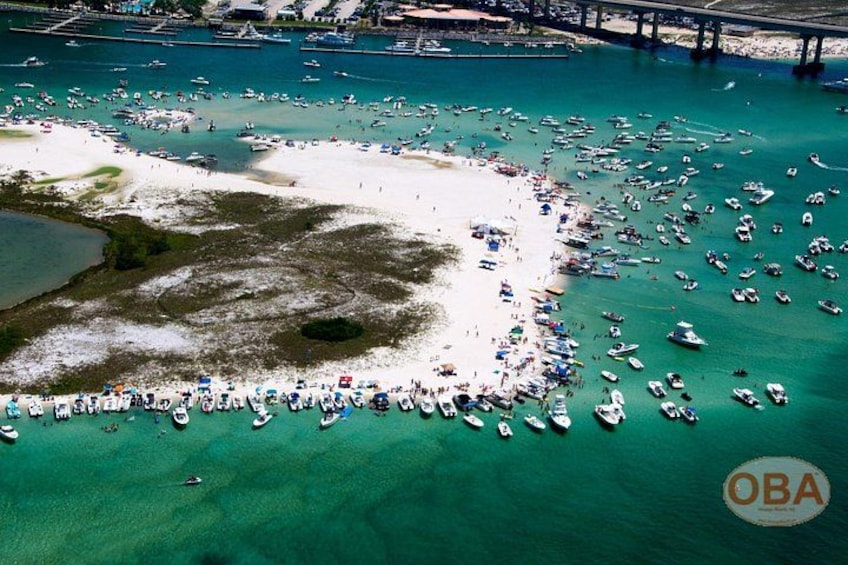Una zona costera con una playa arenosa, numerosos barcos y un puente al fondo. 2